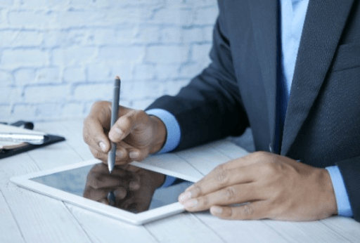 Businessman signing document on tablet with stylus.