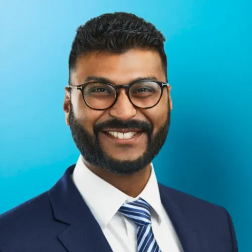 Smiling man in suit and tie with blue background.