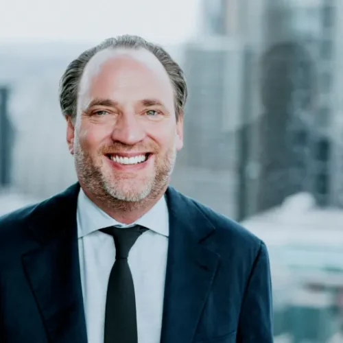 Smiling man in suit with cityscape background.