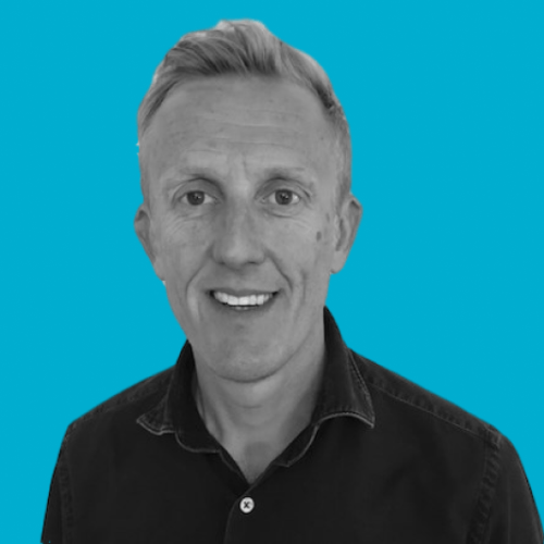 Smiling man with short hair, blue background.